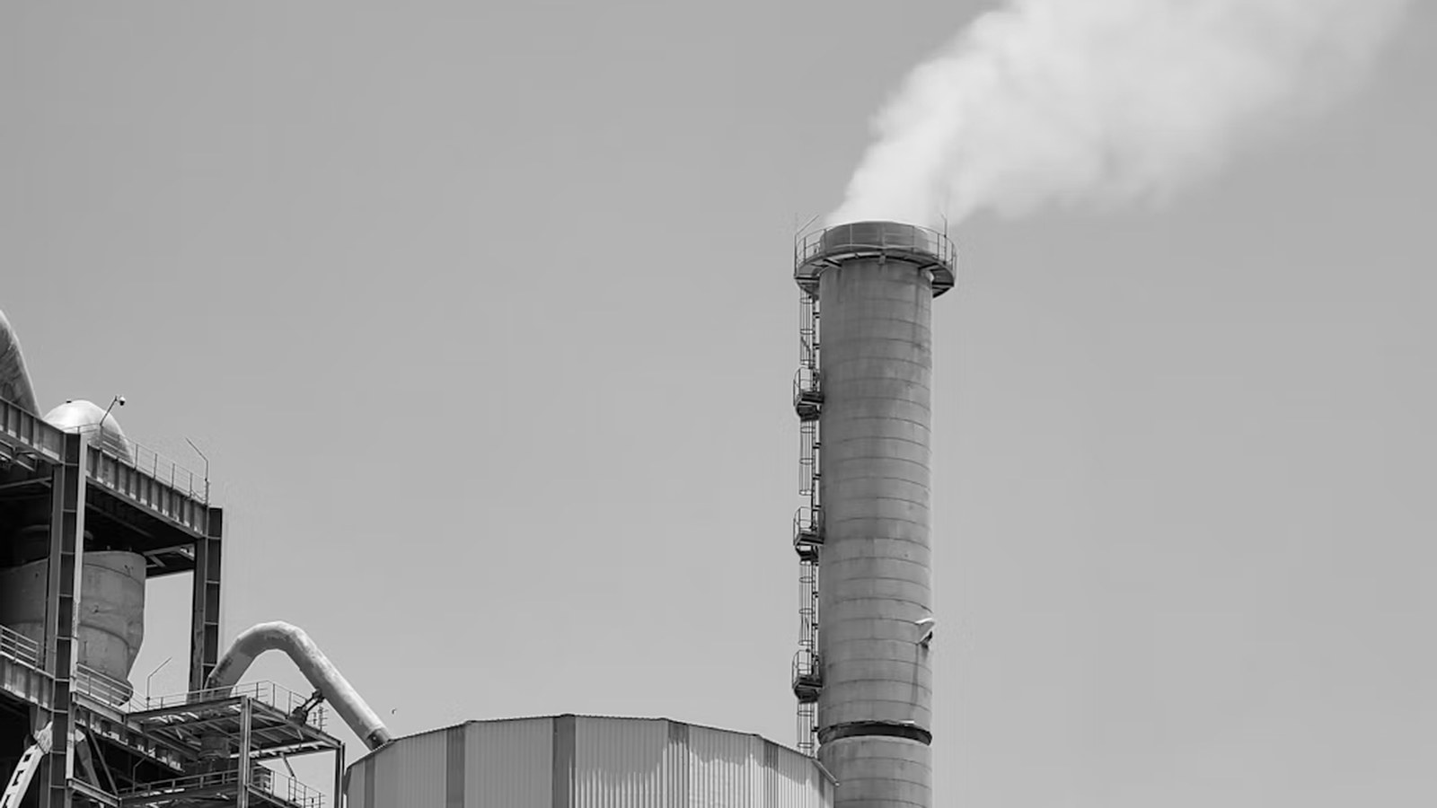 A cement kiln stack venting steam above a cement production plant