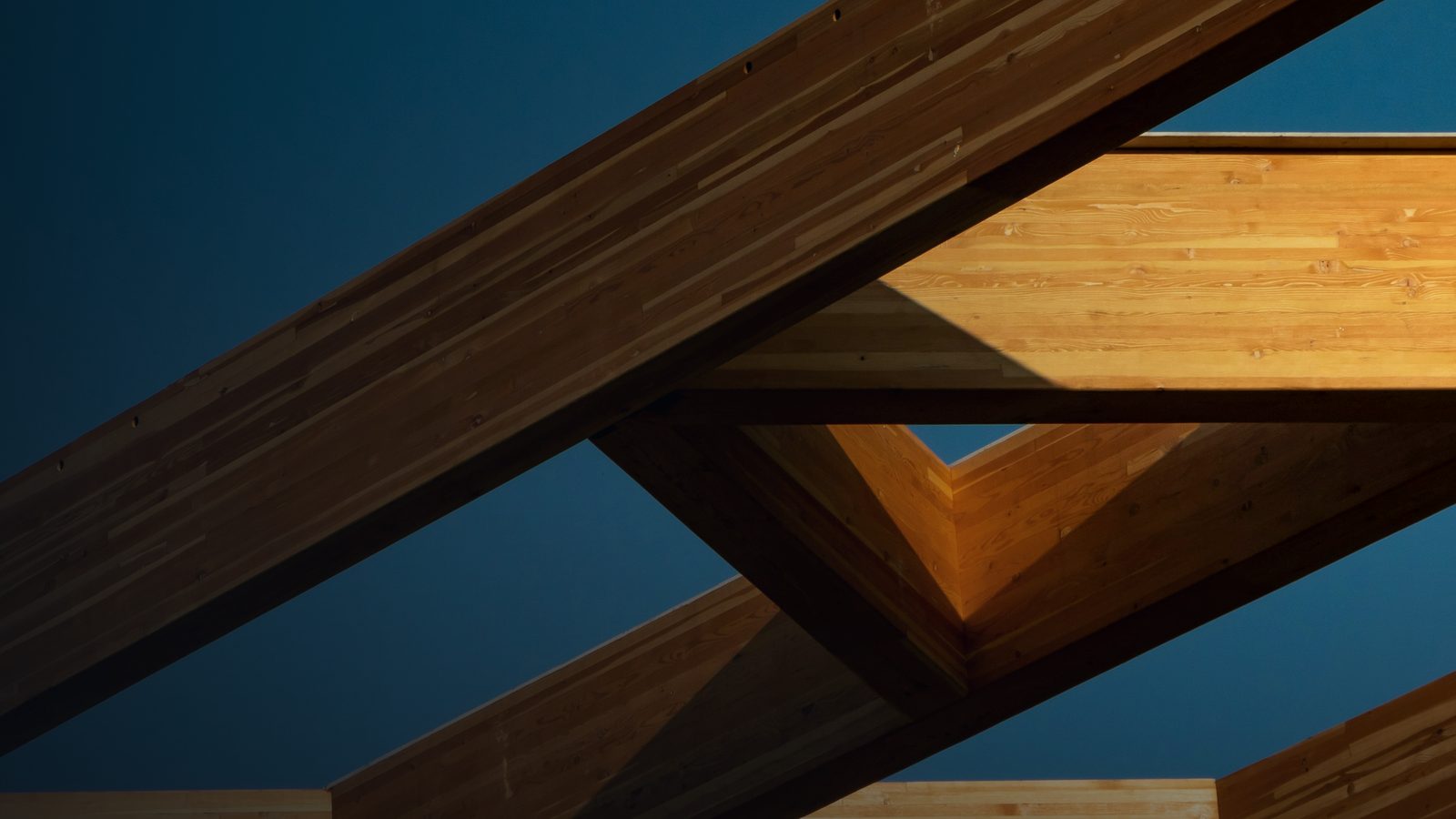 A glulam timber beam junction against a clear sky