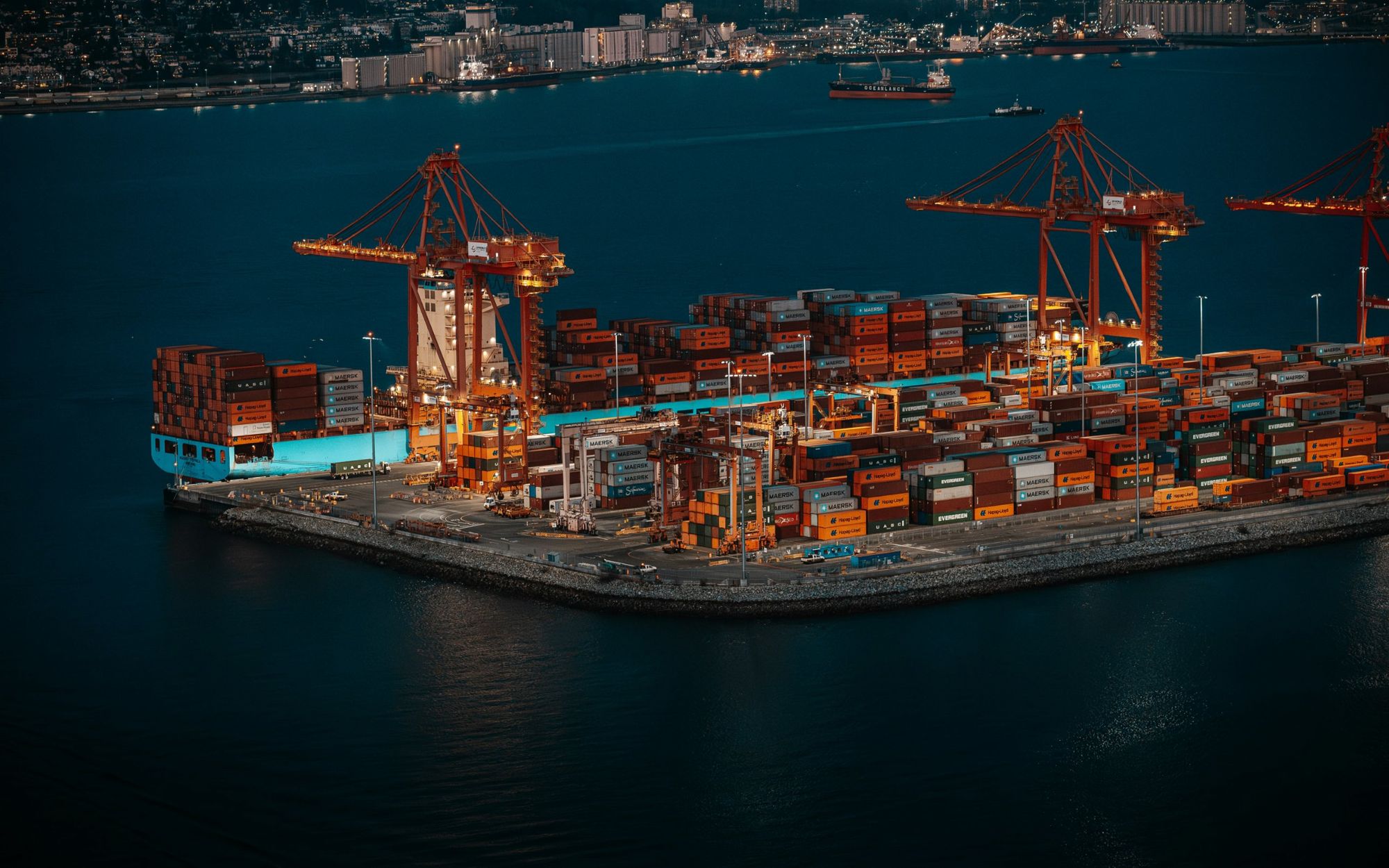 Container port at night with cranes and stacked shipping containers